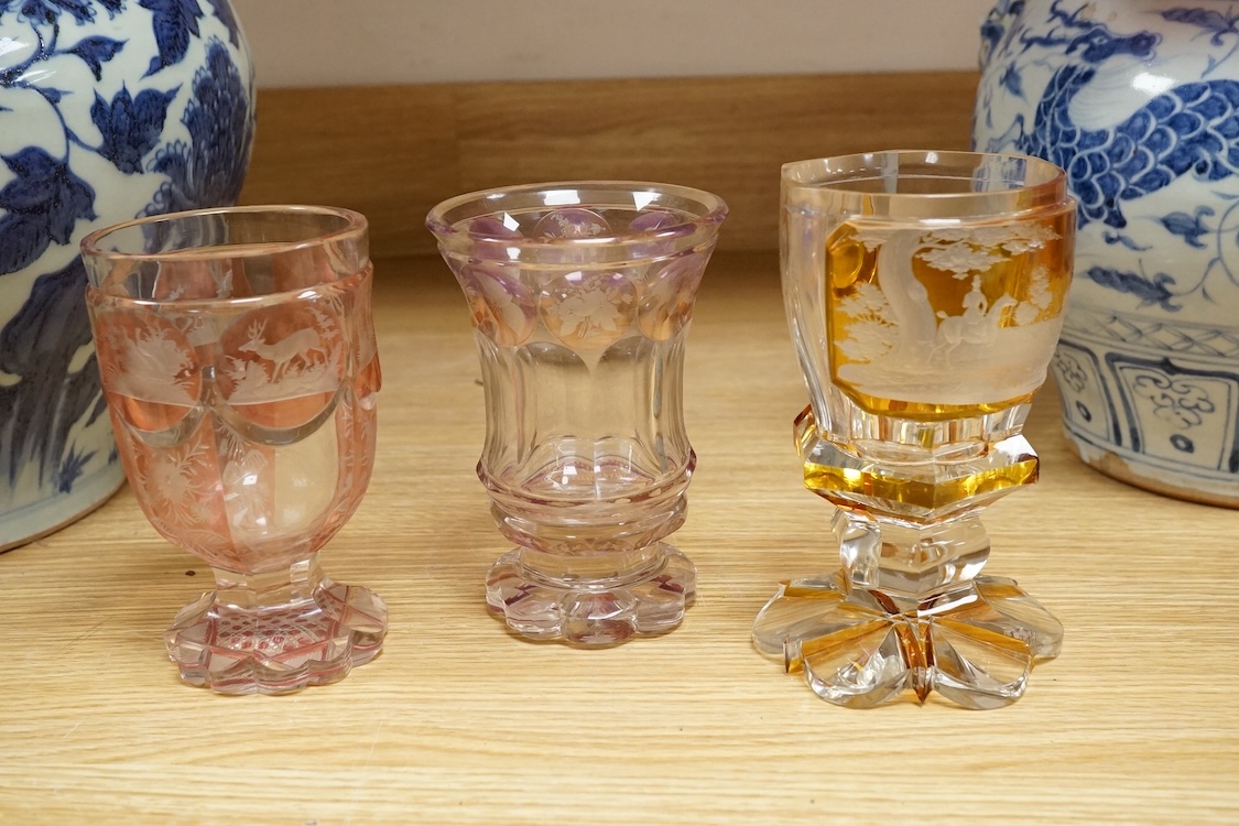 Three Bohemian colour flashed glass goblets, late 19th century, two with hunting subjects, the third decorated with insects, birds and flowers